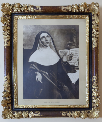 Cadre noir et or. Portrait dessiné. Marie de l’Incarnation, en habit religieux, tournée vers la droite. Mains ouvertes à l’avant pointant vers le ciel. Derrière, un livre ouvert.