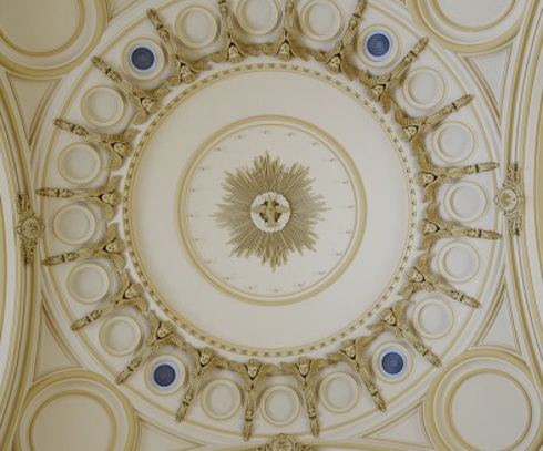 Low relief of the ceiling, vaults. Circular pieces shaped as golden suns. A pelican nourishing its young ones, a flying dove, an anchor with a cross and a sacred heart.