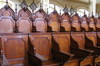 Deux rangées de sièges de bois ouvragé. Plus de quarante sièges. Rangée du fond plus haute avec dossiers en arc et fuseaux décoratifs au haut des dossiers.