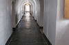 Corridor white vaulted. Large bright window at the bottom. Very thick walls. Doors on each side. Dark stone floor.