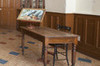 Teacher desk. Rectangular wooden table with a chair with backrest. On the table, an educational painting of a blue jay in a tree.