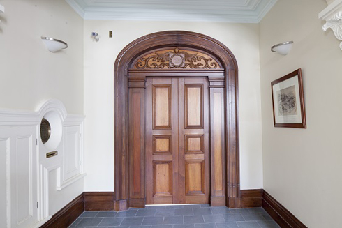 Large wooden door without handle or lock. Large wooden moulding, top ending arched with carved pediment.