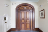 Large wooden door with decorative arch. No handle. White coin.