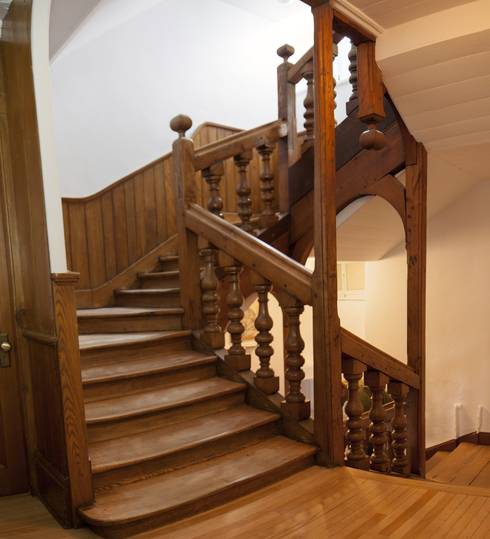 Escalier tournant vers la droite. Tout de bois. Poteaux de rampe ouvragés. Les traces d’usure sont visibles sur les marches.