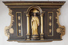 Dans une alcôve de bois brun foncé avec ornements dorés se tient, entre deux petites colonnes dorées un St-Joseph vêtu de doré, sceptre à la main.