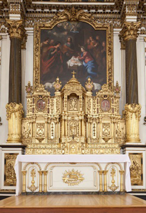 White Altar table with gilded low relief. On it, wide gilded altarpiece and very ornate tabernacle. Two gilded columns.