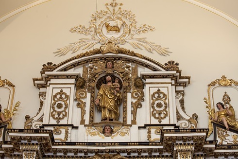 Ornament Upper part of the Chapel wall. Gilded and white alcove overcome by sacred heart low relief. In the center, statue of Saint joseph holding child Jesus in his arms.