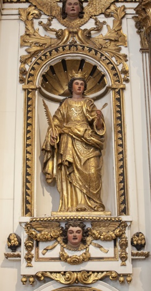 Partie latérale de l’ornement de tête du retable de la chapelle. Petit alcôve doré abritant la sculpture dorée de Ste-Ursule tenant un sceptre.