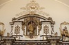 Statue de saint Joseph tenant l’enfant-Jésus. Dorée. Dans une alcôve décorée, surplombant tous les autres ornements.
