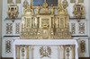 Petit mur latéral de bas-reliefs, tableaux et sculptures. Partie centrale ouvragée et dorée. Table de l’autel accessible par trois marches. 