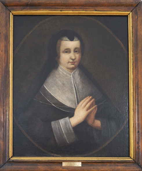 Portrait peint, Madeleine de la Peltrie vêtue de noir, avec voile de veuve du 17e siècle. Elle regarde vers la droite. Mains jointes en prière.