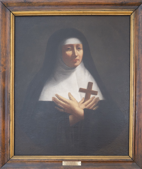 Painted portrait of Marie de st-Joseph de la Troche, in nun clothes, crossed hands on her heart. Holding a wooden cross.