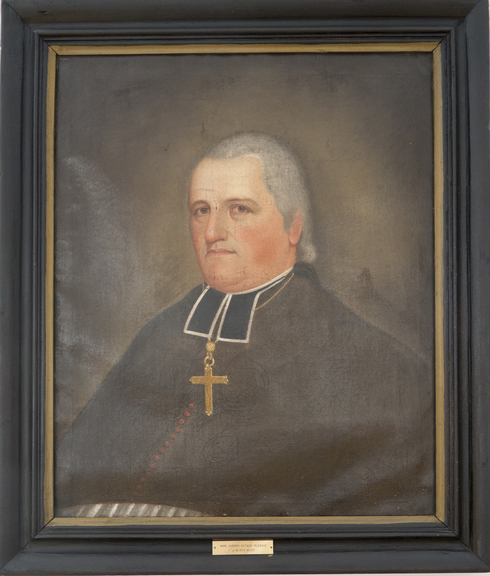 Tableau peint. Cadre de bois noir. Portrait de Monseigneur Plessis dans son habit religieux. Cheveux gris, sans sourire, regard vers la gauche.