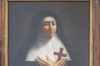 Tableau peint. Portrait de mère St-Joseph. Religieuse : robe et voile noir. Guimpe et bandeau blanc. Mains croisées sur son cœur. Tient une croix de bois.
